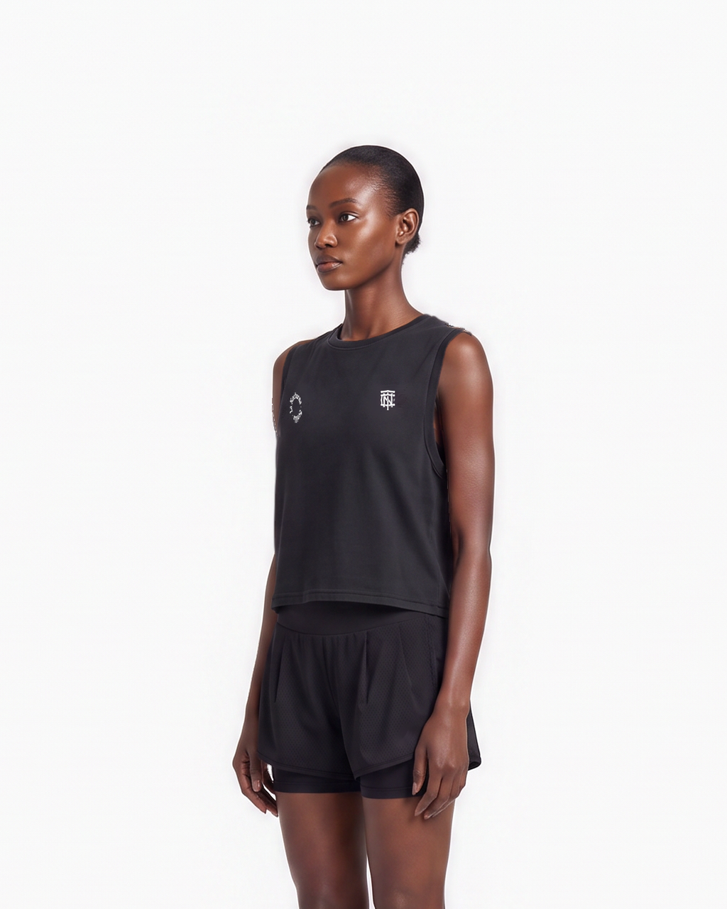Model wearing the Let's Run the Night cropped tank top in black — three-quarter view, close crop on the cropped fit — Ansicht 5