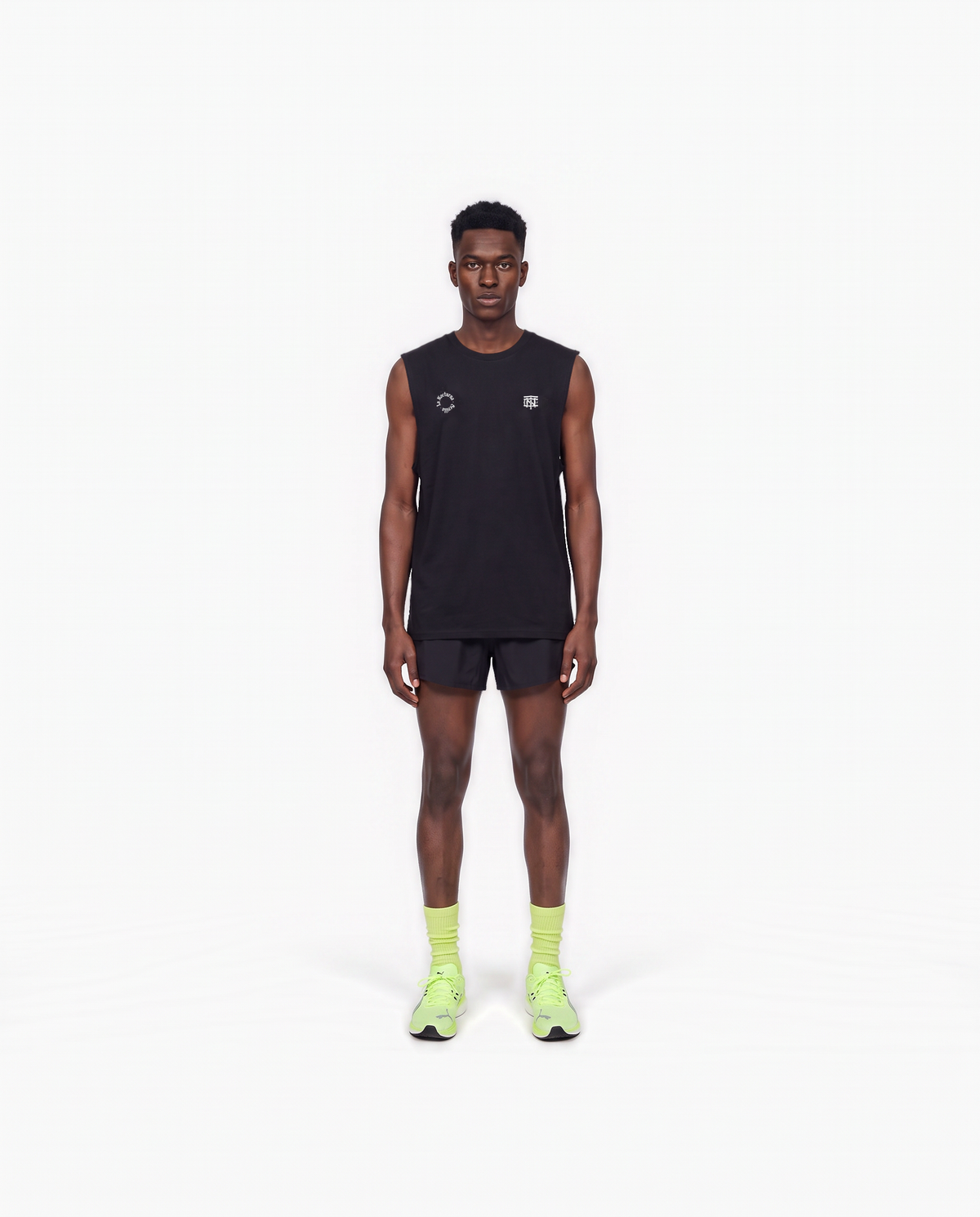 Model wearing the Let's Run the Night tank top in black — front view with the La Nocturna Sevilla seal and the TN monogram in white — Ansicht 2