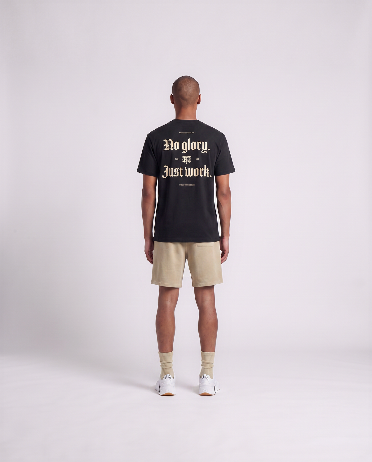 Model wearing the No Glory Just Work t-shirt in black — back view with the NO GLORY JUST WORK blackletter print in sand with the Thundernoise monogram — Ansicht 4