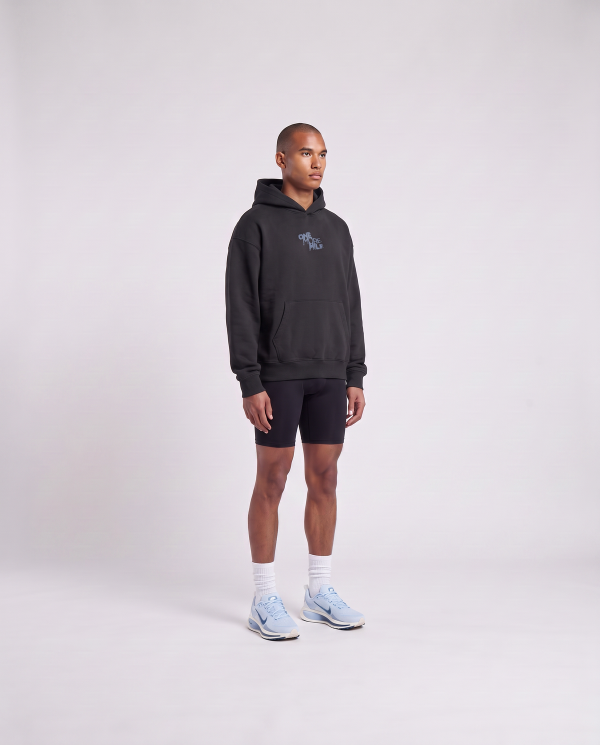 Model wearing the One More Mile oversize hoodie in black — three-quarter view showing the oversize fit — Vista 3