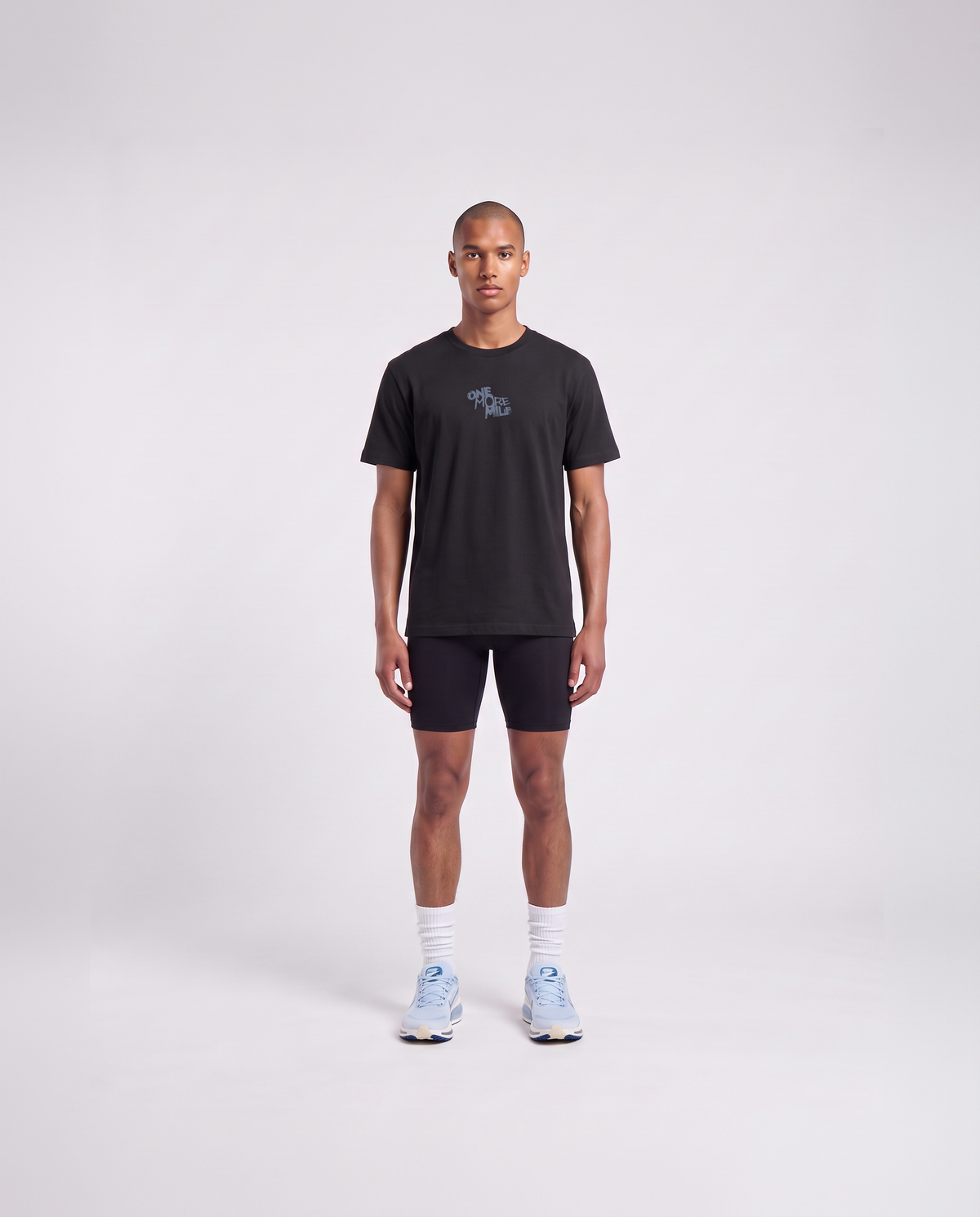 Model wearing the One More Mile t-shirt in black — front view with the ONE MORE MILE graffiti mark at the chest in slate blue — Ansicht 2