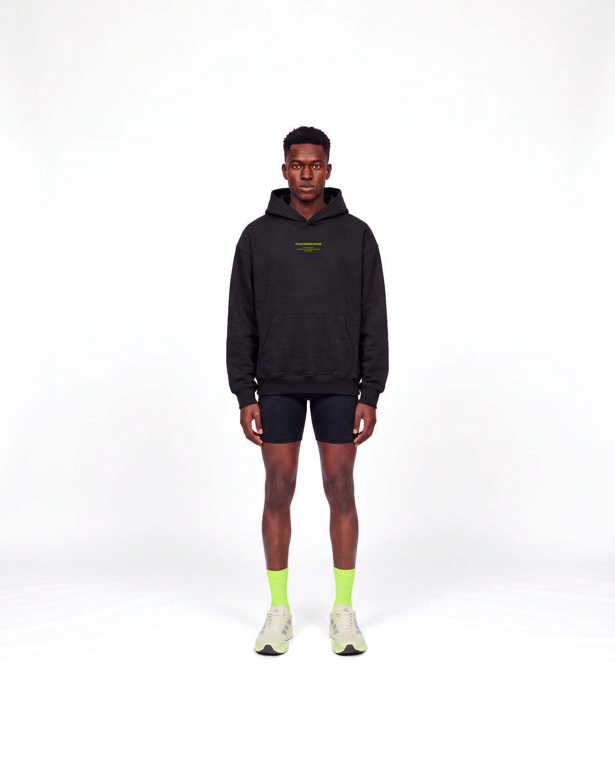 Model wearing the Brick by Brick oversize hoodie in black — front view with the THUNDERNOISE TRAINING DEPT block centred on the chest in lime green — Ansicht 2
