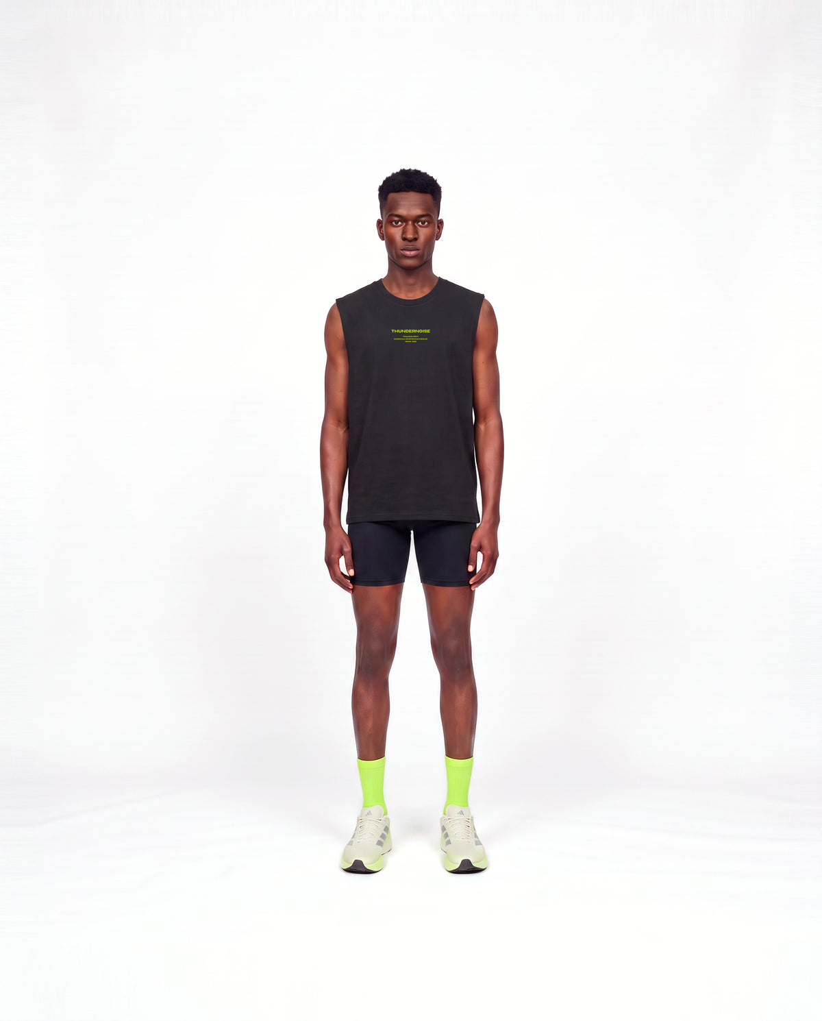 Model wearing the Brick by Brick tank top in black — front view with the THUNDERNOISE TRAINING DEPT block centred on the chest in lime green — Vista 2
