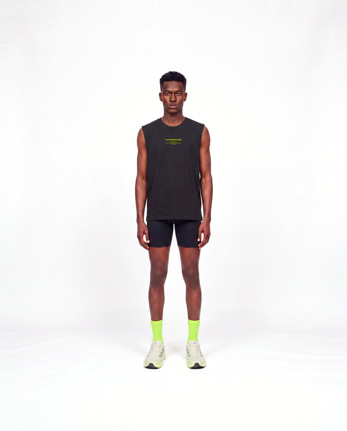 Model wearing the Brick by Brick tank top in black — front view with the THUNDERNOISE TRAINING DEPT block centred on the chest in lime green