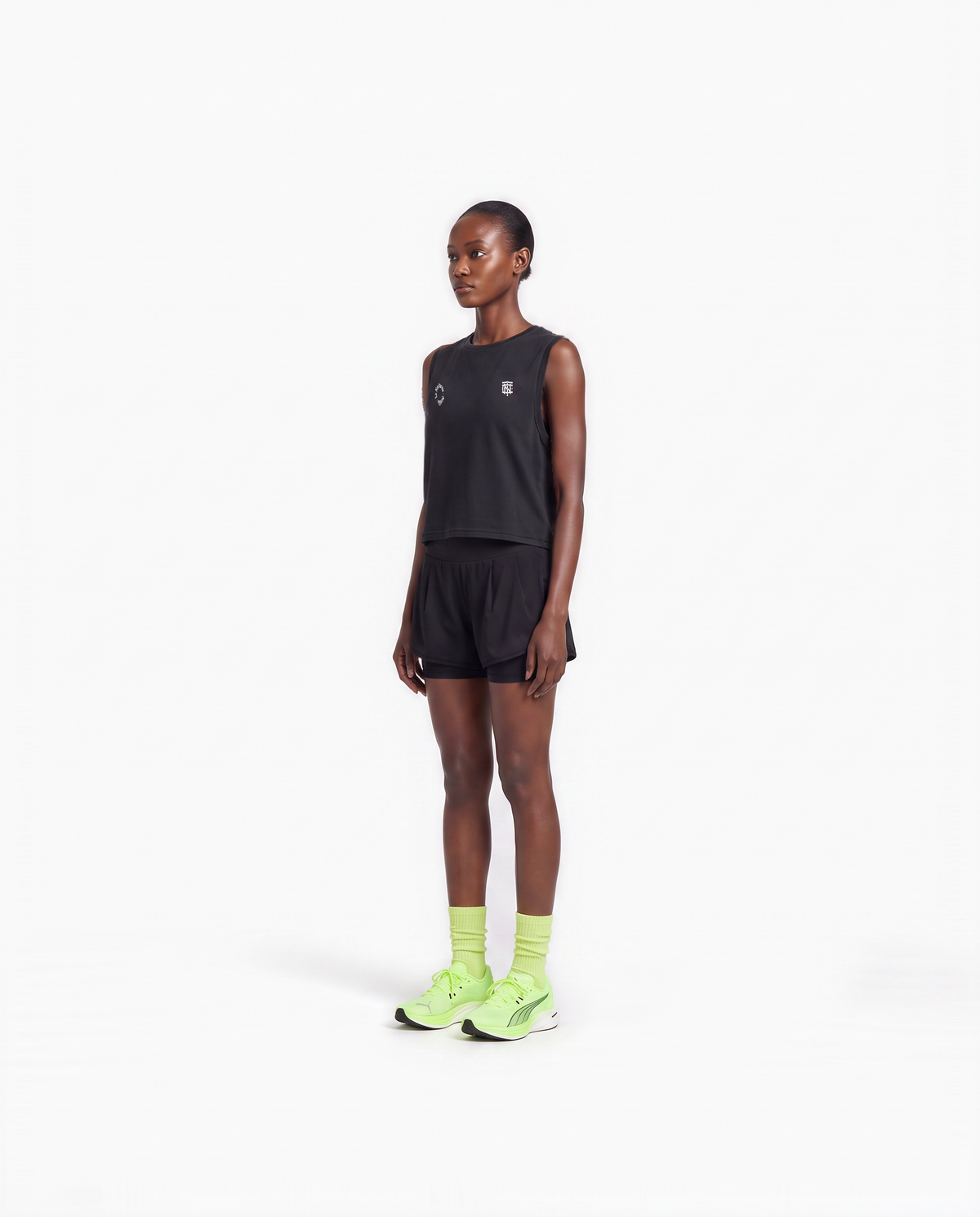 Model wearing the Let's Run the Night cropped tank top in black — three-quarter view showing the cropped fit — Ansicht 4
