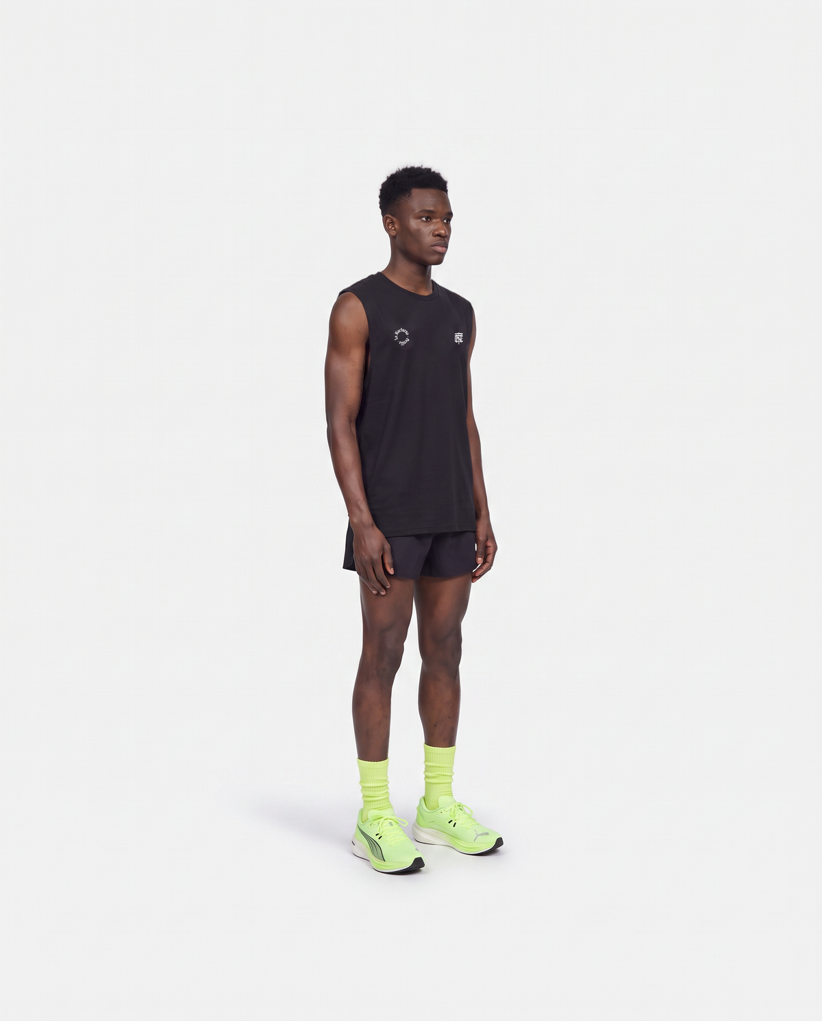 Model wearing the Let's Run the Night tank top in black — three-quarter view showing the regular fit — Vista 4
