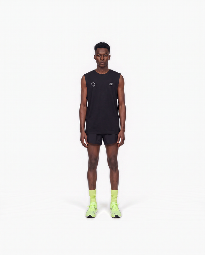 Model wearing the Let's Run the Night tank top in black — front view with the La Nocturna Sevilla seal and the TN monogram in white