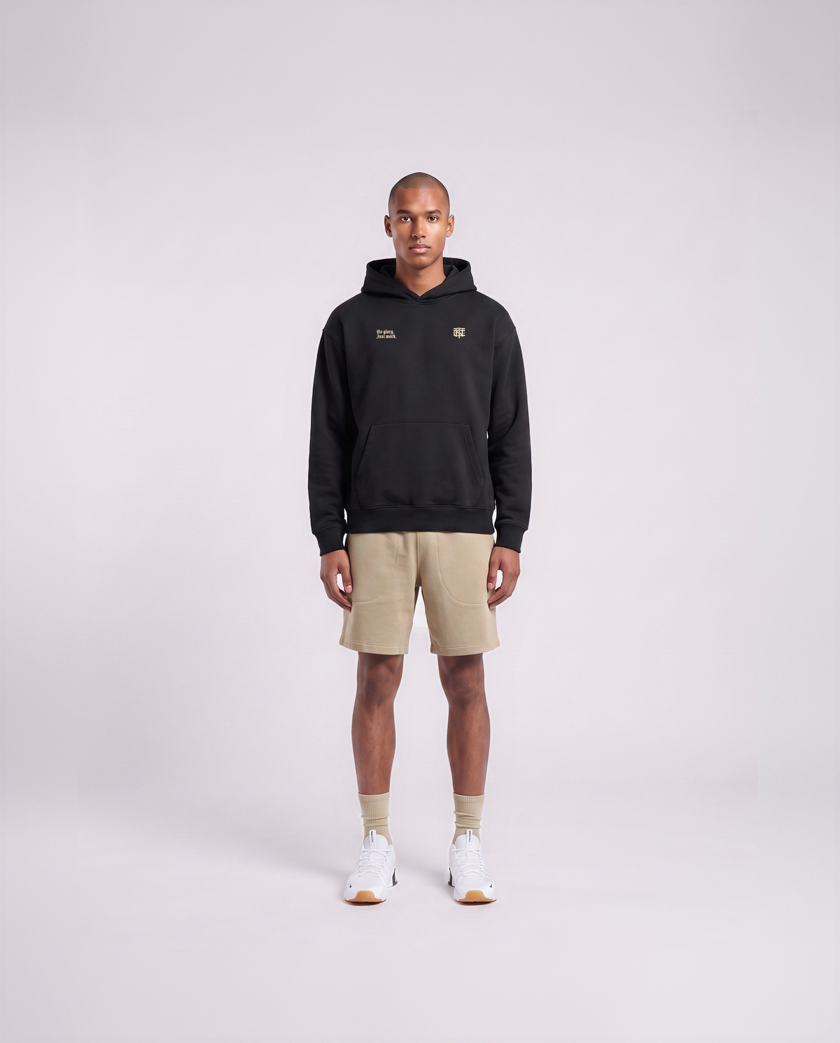 Model wearing the No Glory Just Work oversize hoodie in black — front view with the left-chest NO GLORY JUST WORK wordmark and the right-chest Thundernoise monogram in sand — Ansicht 2
