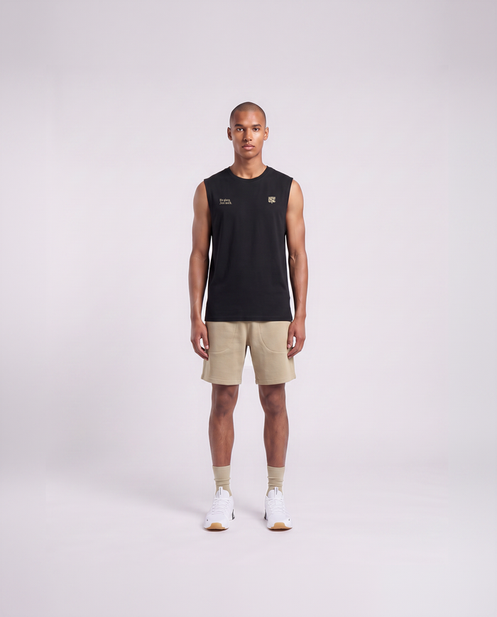 Model wearing the No Glory Just Work tank top in black — front view with the left-chest NO GLORY JUST WORK wordmark and the right-chest Thundernoise monogram in sand