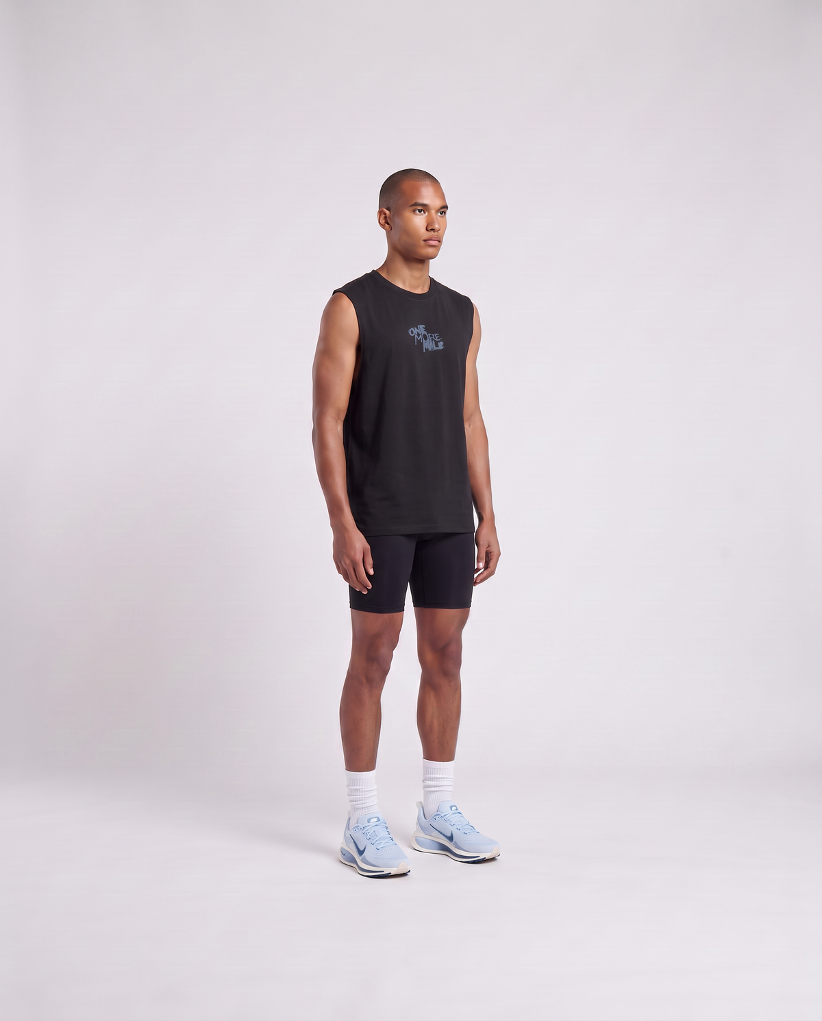 Model wearing the One More Mile tank top in black — three-quarter view showing the regular fit