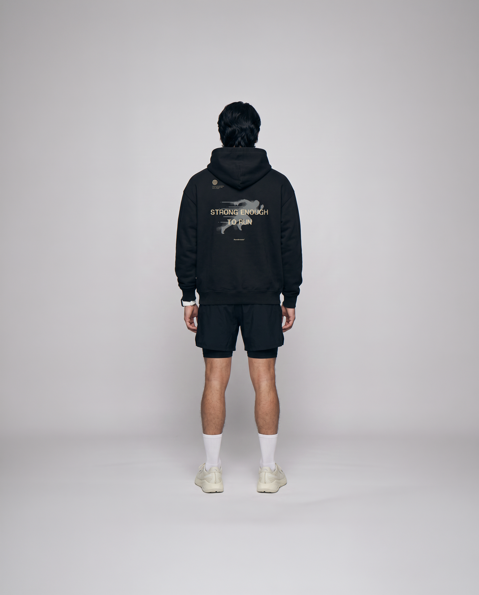 Model wearing the Strong Enough to Run oversize hoodie in black — back view with the STRONG ENOUGH TO RUN halftone runner print — Vue 3
