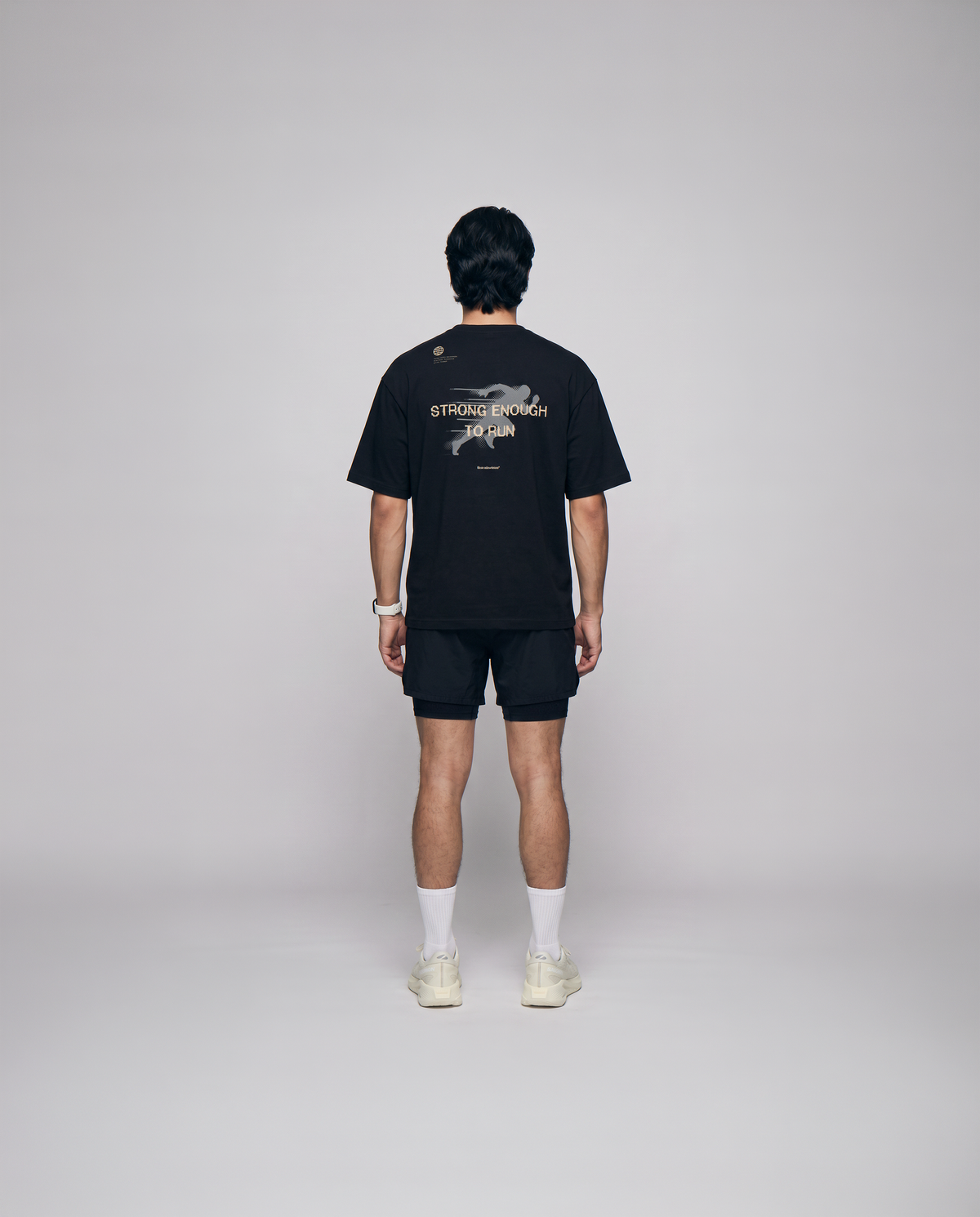 Model wearing the Strong Enough to Run oversize t-shirt in black — back view with the STRONG ENOUGH TO RUN halftone runner print — Ansicht 3
